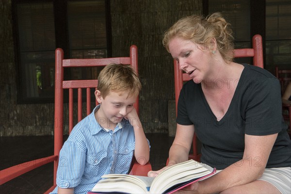 Caucasian mother and son reading on patio