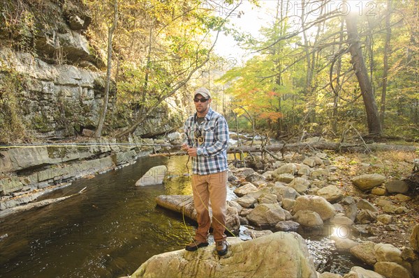 Caucasian man fishing in forest steam