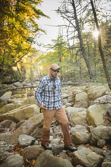 Caucasian man fishing in forest steam