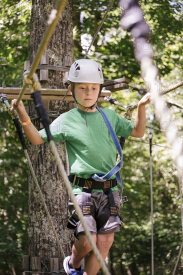 Caucasian boy balancing on rope bridge