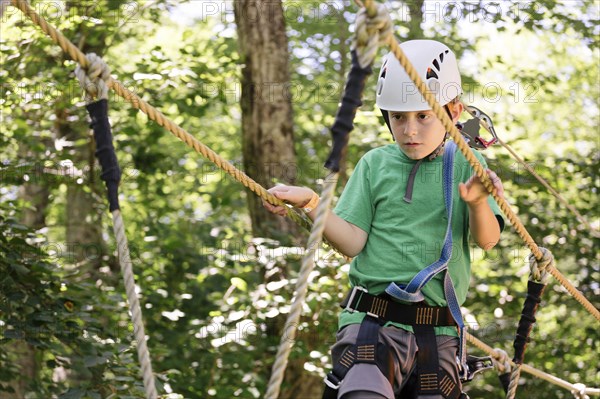 Caucasian boy balancing on rope bridge