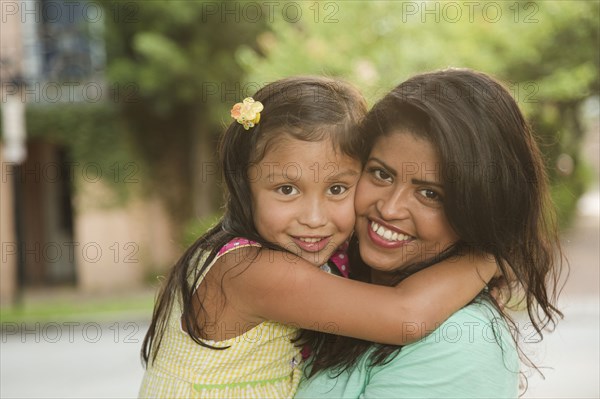 Hispanic mother hugging daughter