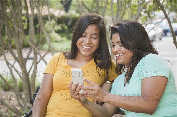 Hispanic mother and daughter posing for cell phone selfie