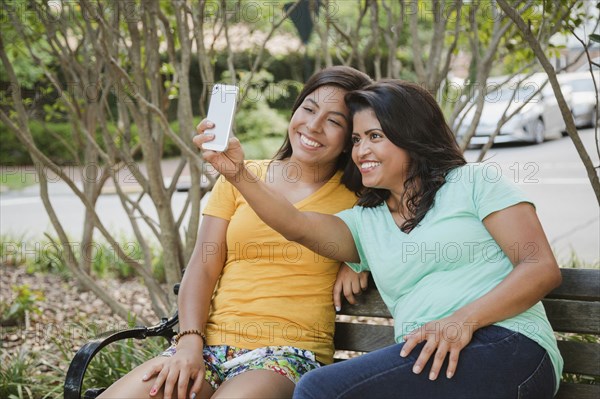 Hispanic mother and daughter posing for cell phone selfie