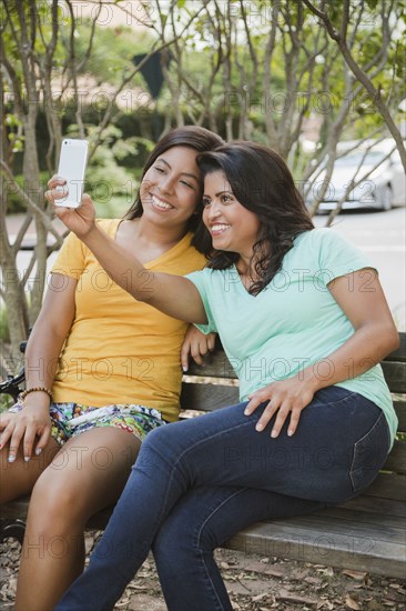 Hispanic mother and daughter posing for cell phone selfie