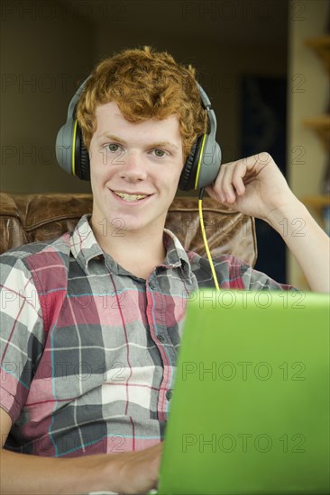 Portrait of smiling Caucasian boy listening to laptop with headphones