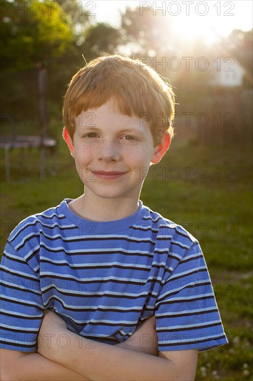 Smiling Caucasian boy standing in sunny backyard