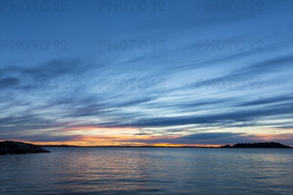 Clouds in sunset sky over still ocean