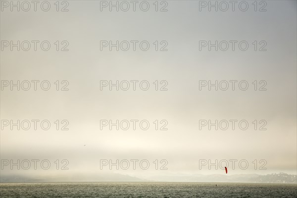 Kiteboarder on ocean under cloudy sky