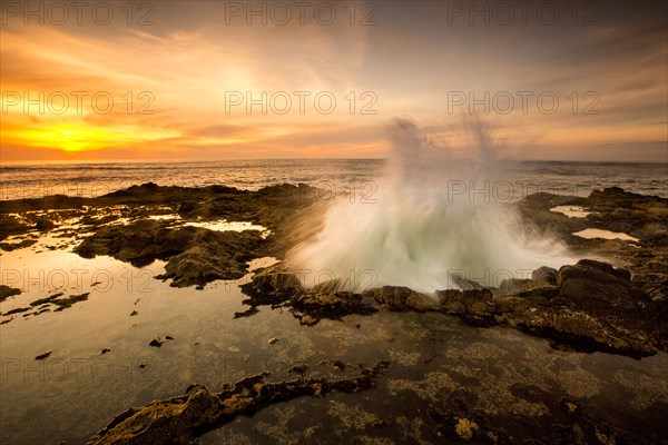 Ocean waves crashing in Thor's Well at sunset