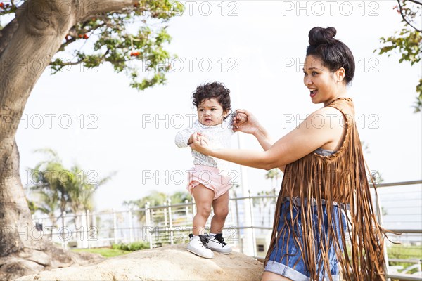 Mother playing with baby son in park