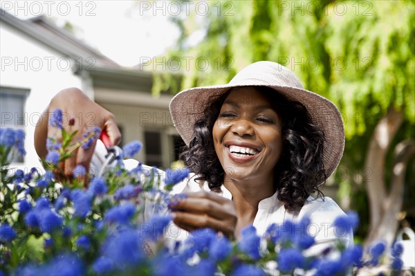 Smiling woman pruning flowers in garden