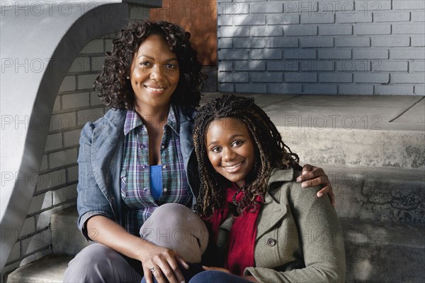 Black mother and daughter sitting on front stoop