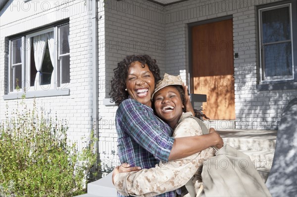 Black mother hugging soldier daughter