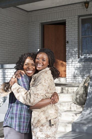 Black mother hugging soldier daughter