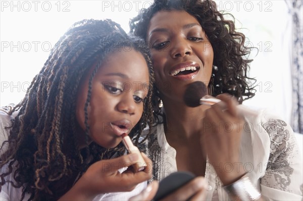 Black mother and daughter putting on makeup