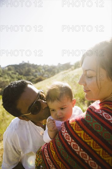 Mother watching father kissing baby