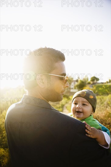 Father holding baby in field