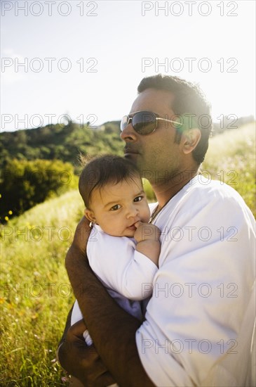 Father holding baby in field