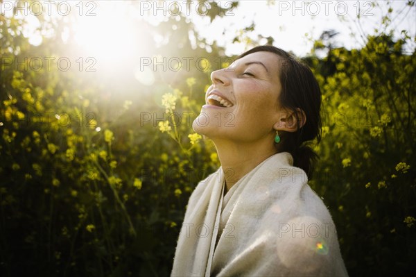 Laughing mixed race woman with eyes closed in field