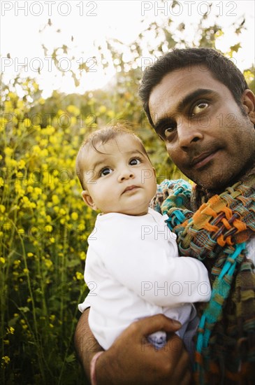 Father holding baby in field