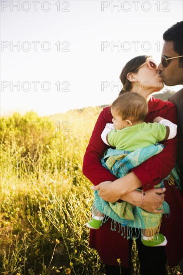 Mother holding baby and kissing husband