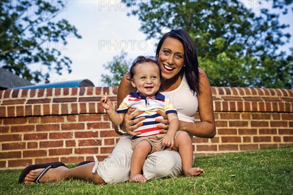 Mixed race mother and son sitting in grass