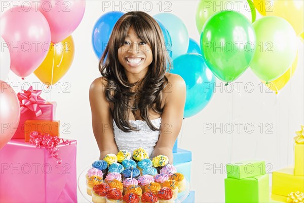 African American woman with birthday presents and cupcakes