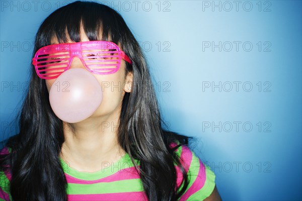 Mixed race woman blowing bubble with bubble gum