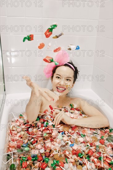 Mixed race woman taking a bath in candy