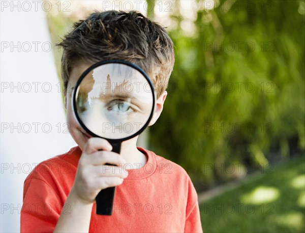Caucasian boy looking through magnifying glass