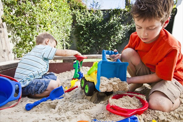 Caucasian brothers playing in sandbox