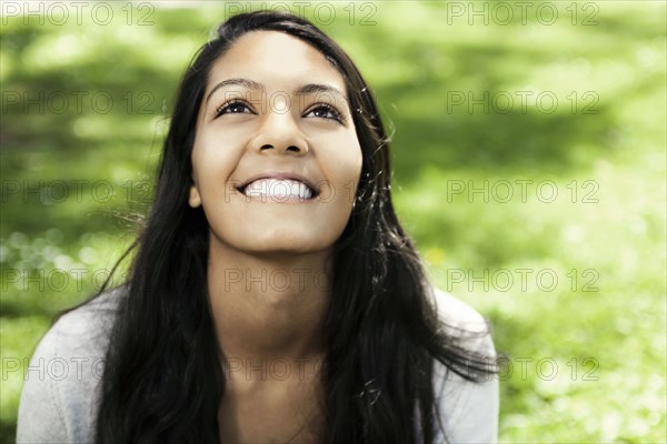 Smiling Hispanic teenager sitting in grass
