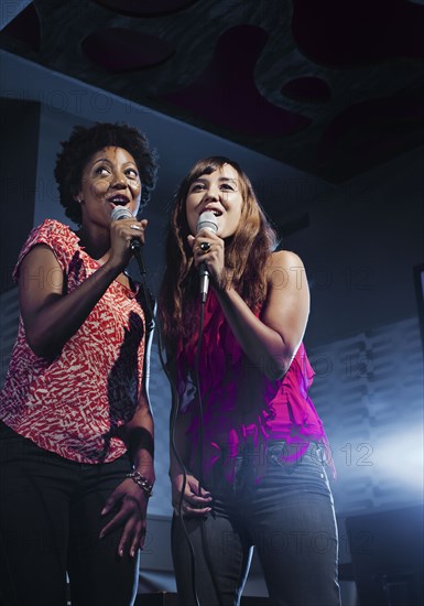 Friends singing karaoke in nightclub