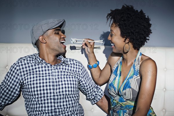 Woman feeding boyfriend sushi with chopsticks