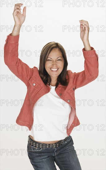Portrait of Hispanic woman smiling with arms raised
