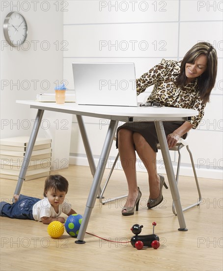 Hispanic working mother and baby son in home office