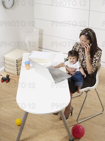 Hispanic working mother and baby son in home office