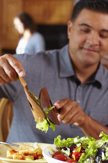 Mixed race man serving himself salad