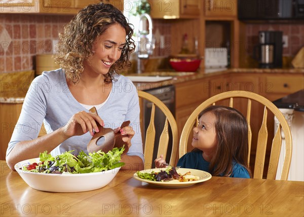 Mother serving daughter salad