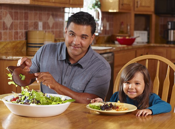 Father serving daughter salad