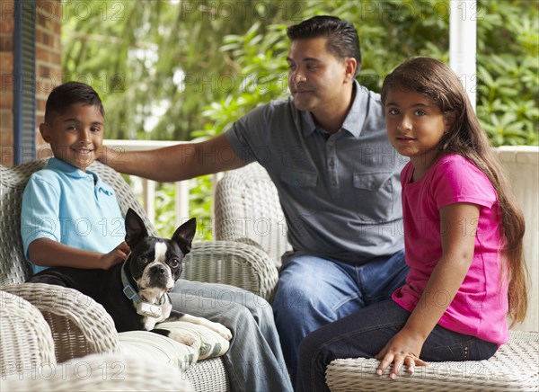 Father and children sitting on porch with dog