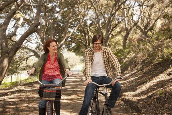 Couple riding bicycles on rural road