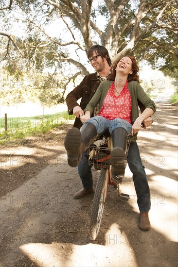 Couple riding bicycle on rural road