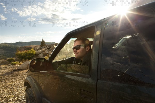 Man sitting in car overlooking rural landscape