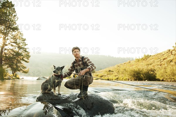 Man with dog fishing in river