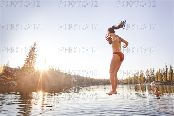 Woman jumping into rural lake