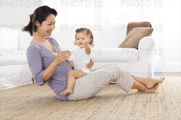 Mother playing with baby girl in living room