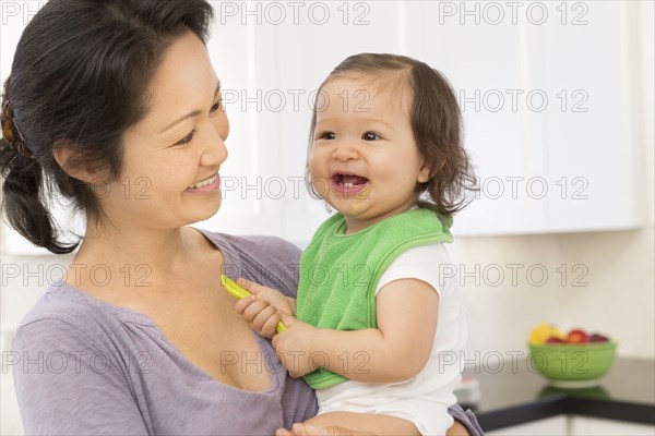 Mother holding baby girl in kitchen