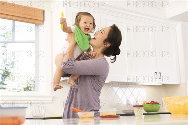 Mother holding baby girl in kitchen